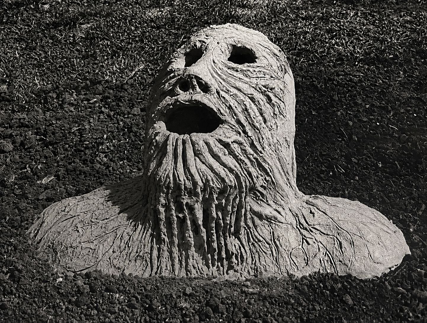 A roughly modelled clay bust with hollow eyes, an open mouth and an elongated neck.